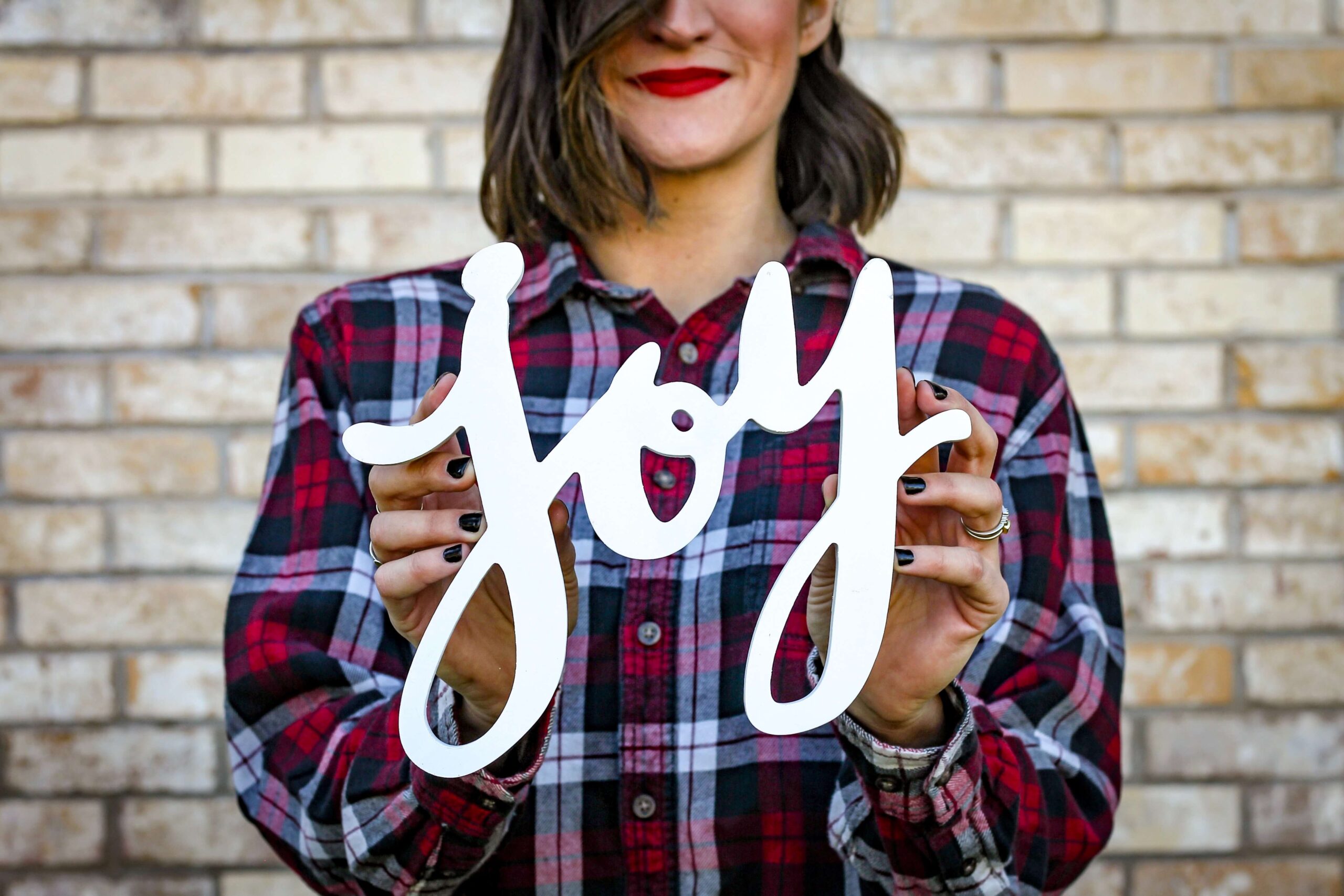 finding joy in lockdown - woman in checked shirt holding the word 'joy' in white letters